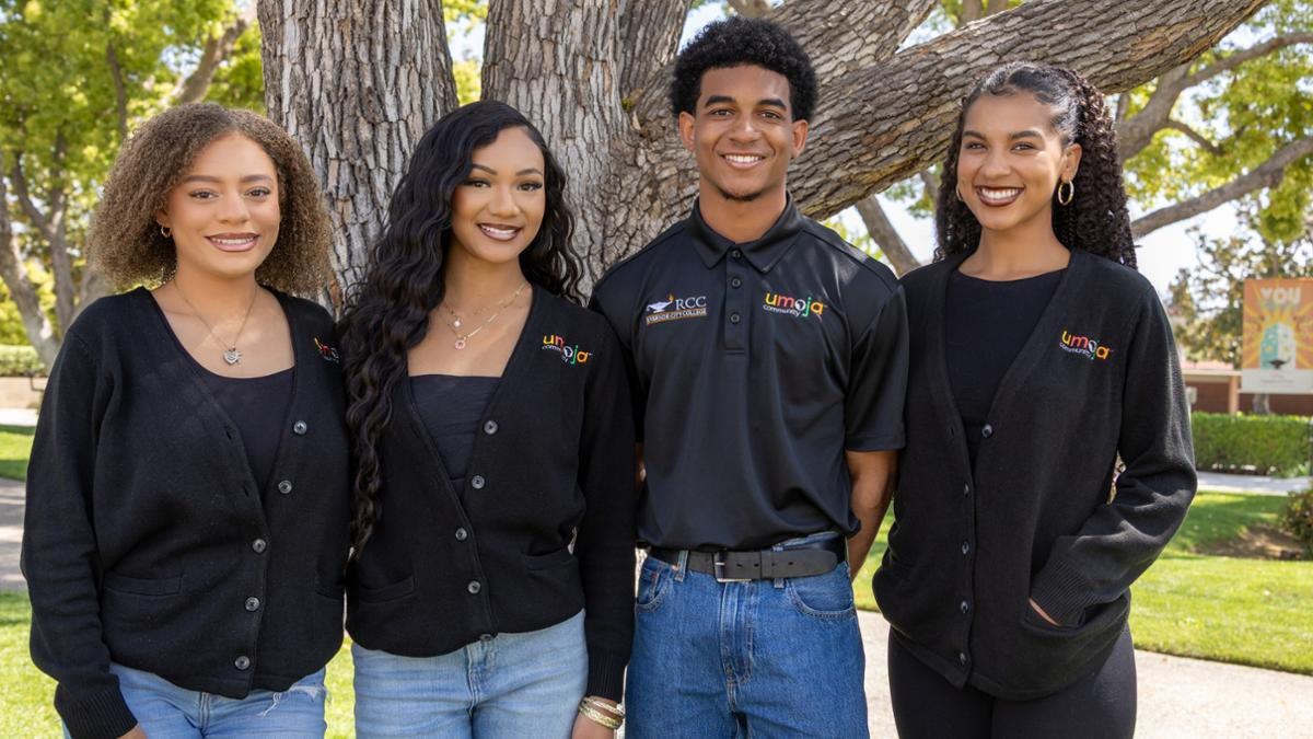 Smiling students from the Umoja program standing in front of a tree