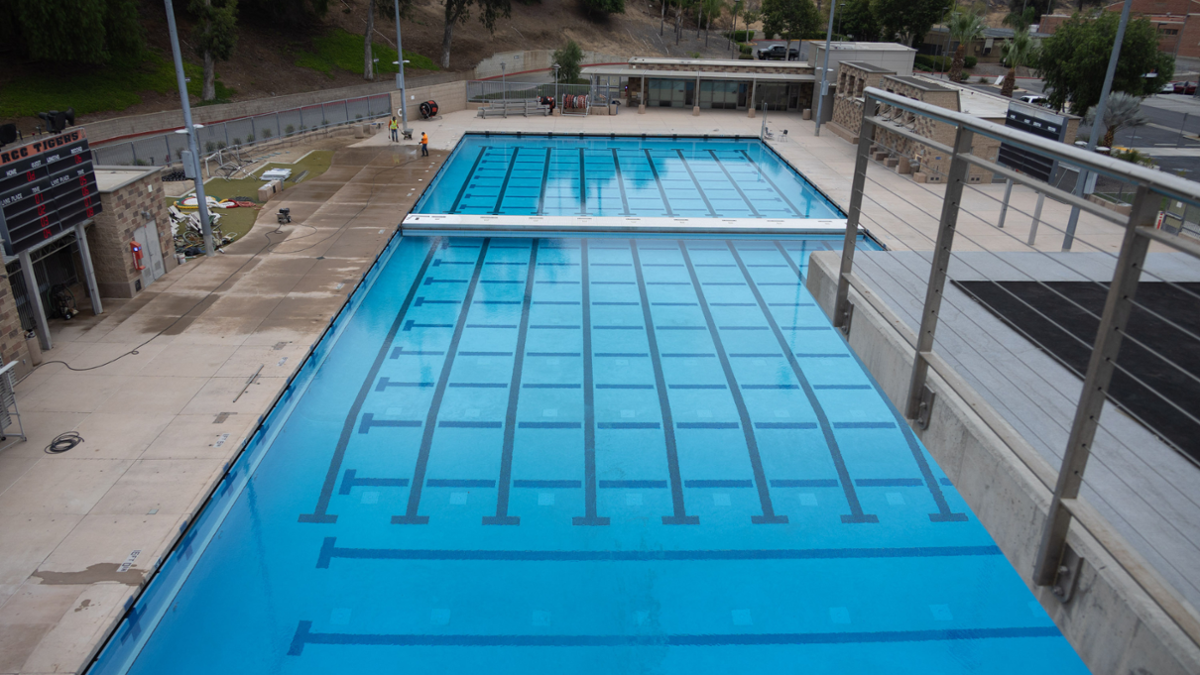 Refurbished Riverside City College swimming pool viewed from above, featuring newly resurfaced lanes, clear blue water, and upgraded pool deck facilities.