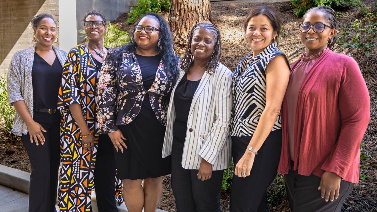 Six women administrators stand together outdoors at Riverside City College during Women’s History Month. The graphic reads “Women of Color in Administration – Riverside City College Women’s History Month