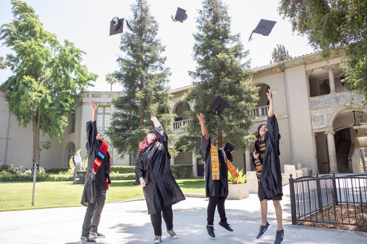 Students in regalia throughing cap into air