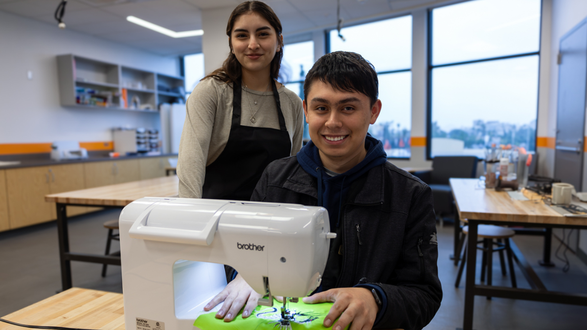 Students in the makerspace working on a sewing machine