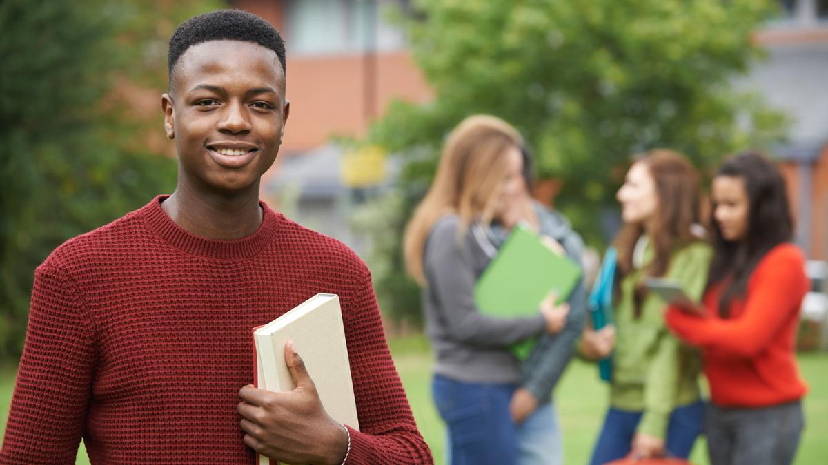 Student with book smiling at the camera